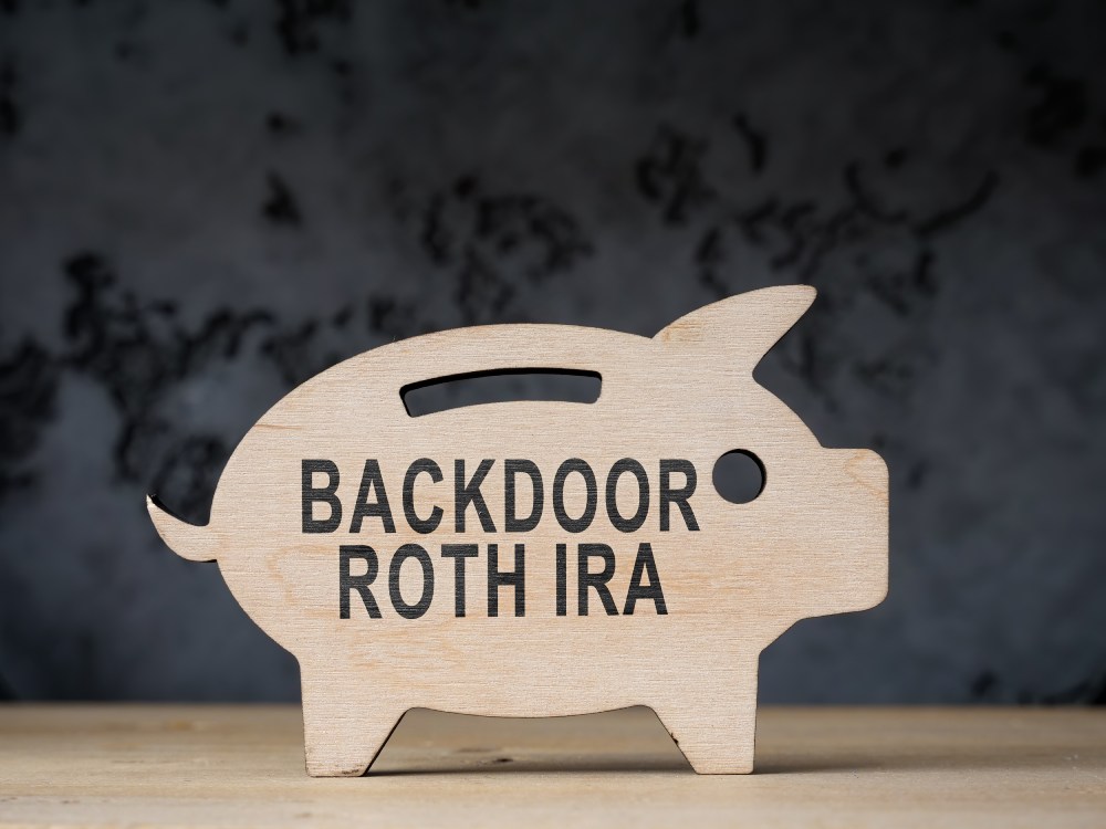 A Guide to Individual Retirement Accounts (IRAs) 8 Wooden piggy-bank cut-out that reads “Backdoor Roth IRA” on a dark background