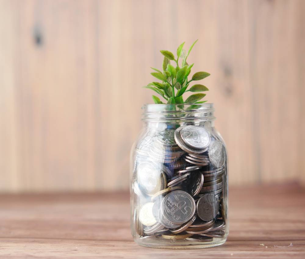 5 Ways to Stay Confident in Retirement 5 Glass jar full of coins with a small green plant sprouting from the top