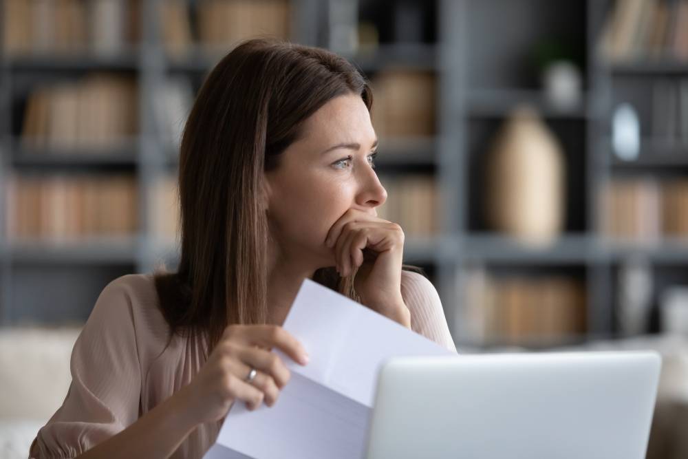 5 Ways to Stay Confident in Retirement 3 Woman at a laptop looking pensively at a bill she is holding