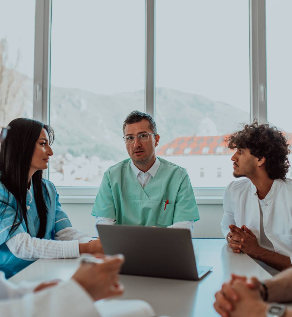 5 Financial Mistakes Physicians Make (And How to Help Avoid Them) 3 Three doctors in a meeting around a table with a laptop