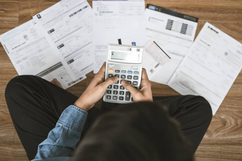 5 Ways to Stay Confident in Retirement 4 Person on the floor using a calculator amid spread-out financial statements