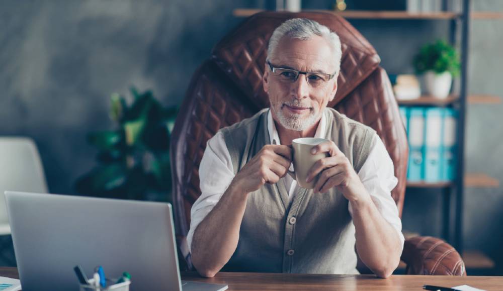 Estate Strategies: Critical Elements of an Estate Plan 2 Older man with a coffee cup at a desk with a laptop