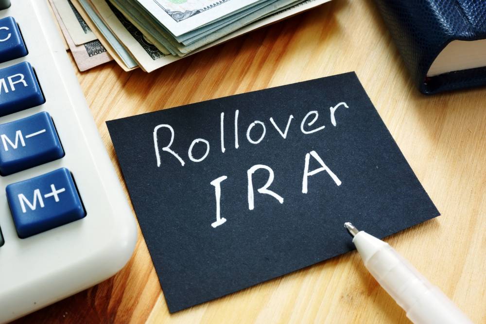 A Guide to Individual Retirement Accounts (IRAs) 6 Black card reading “Rollover IRA” beside a calculator, cash and a pen