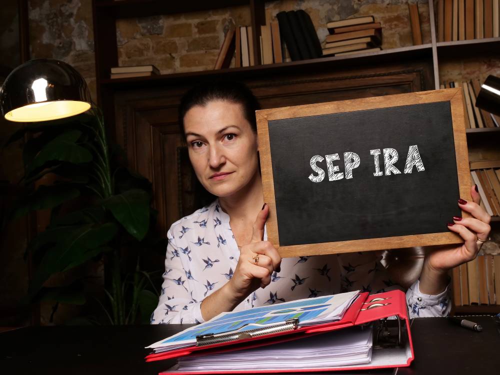 A Guide to Individual Retirement Accounts (IRAs) 4 Woman at a desk holding a small chalkboard that reads “SEP IRA”