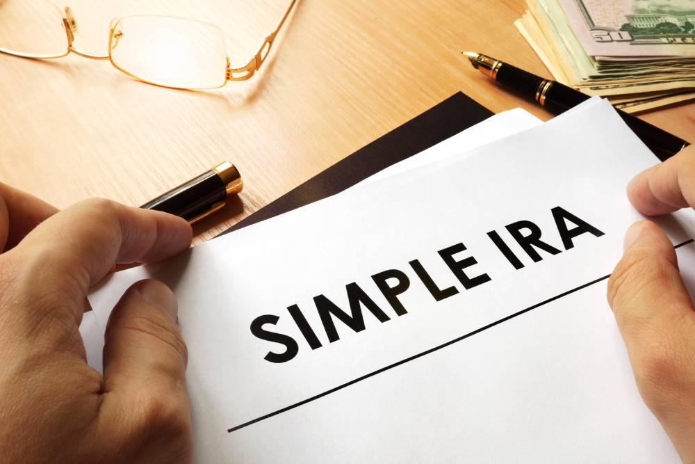 A Guide to Individual Retirement Accounts (IRAs) 5 Hand holding a sheet of paper that reads “SIMPLE IRA” over a desk