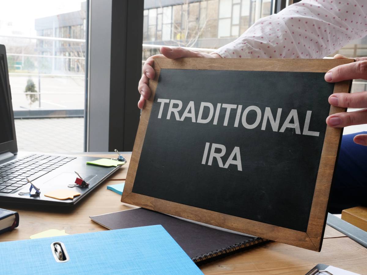 A Guide to Individual Retirement Accounts (IRAs) 1 Hands holding a chalkboard that reads “Traditional IRA” above a laptop on a desk